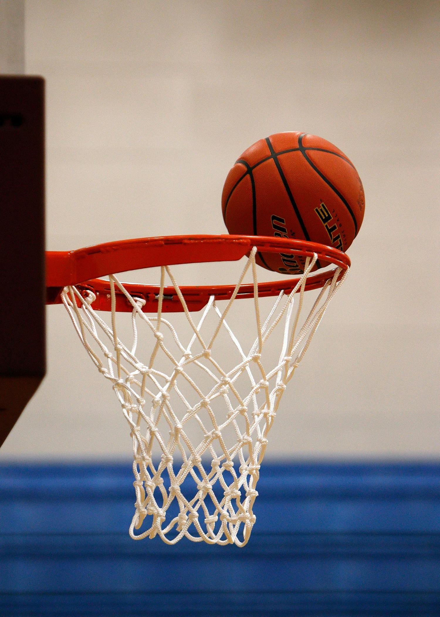 A basketball moment captured as the ball rests on the rim, highlighting the suspense of the game.